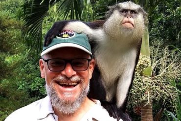 Professor posing with a small ape on his shoulder